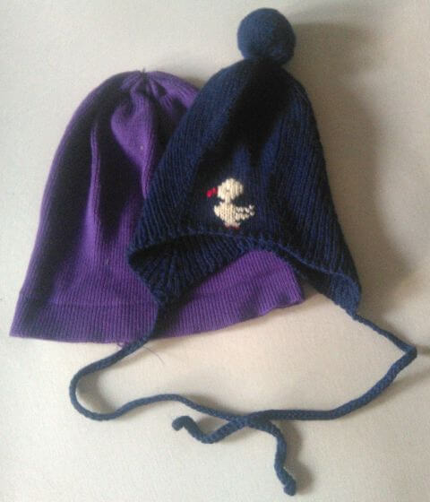 zwei Mützen, eine davon mit aufgesticktem Vogel