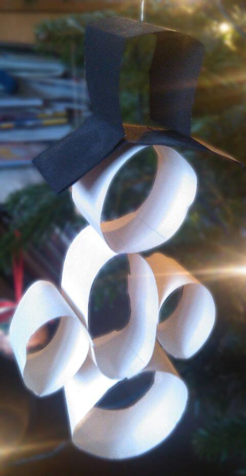 Schneemann aus weißen und schwarzen Papierstreifen an einem Weihnachtsbaum