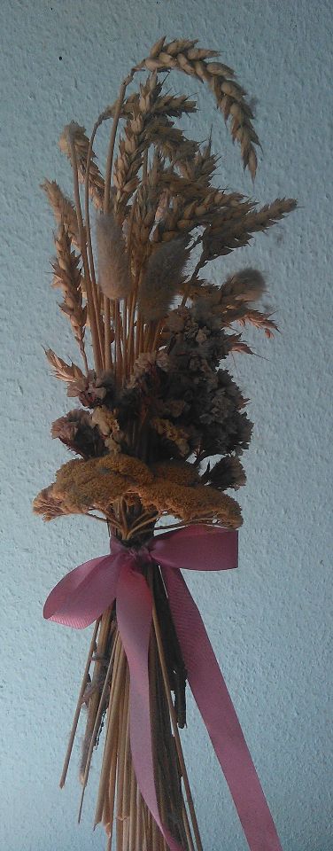 Erntestecken aus Ähren und getrockneten Blumen mit einer Schleife