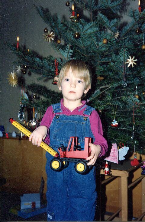 Ich stehe vor dem Weihnachtsbaum und halte einen Fischertechnik-Kranwagen