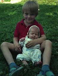 Ich sitze mit einem Baby oder einer Puppe im Schoß auf einer Wiese